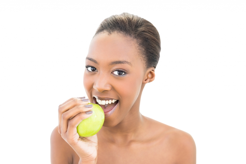 Cheerful natural beauty biting green apple on white background